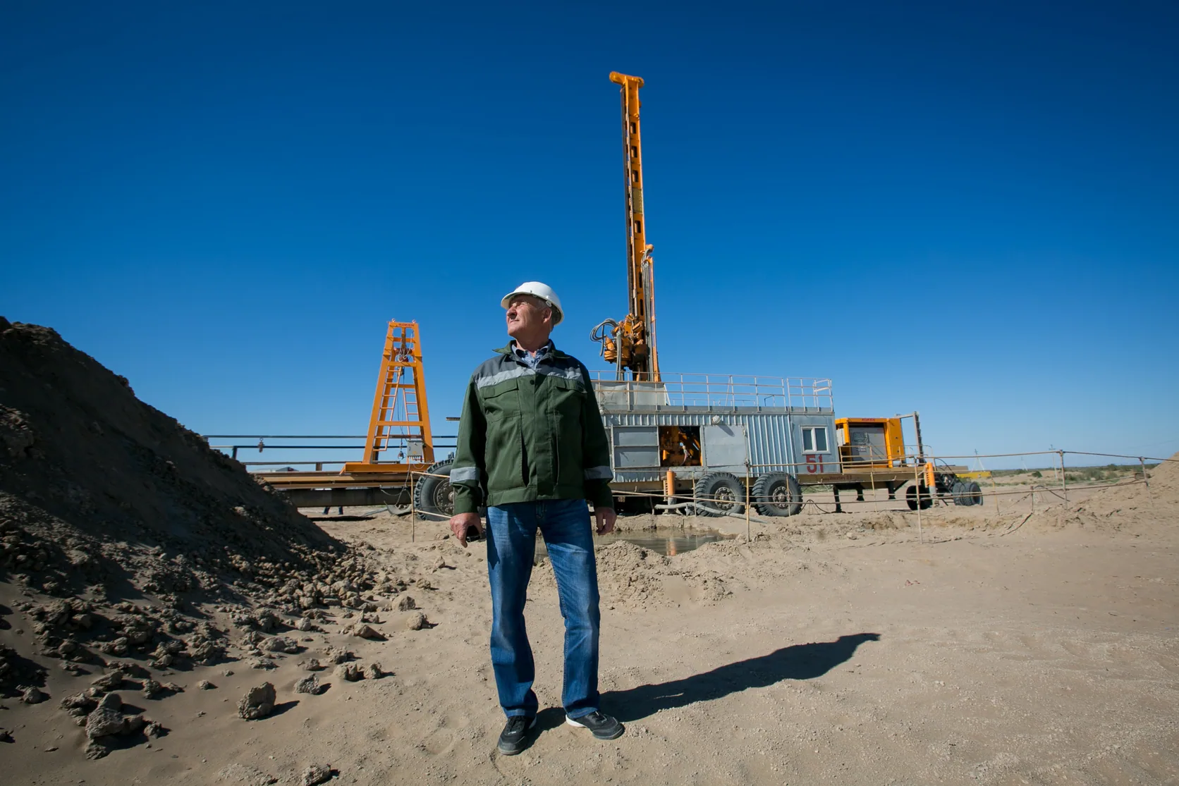 A specialist at a Volkovgeology JSC operating site beside a drilling rig